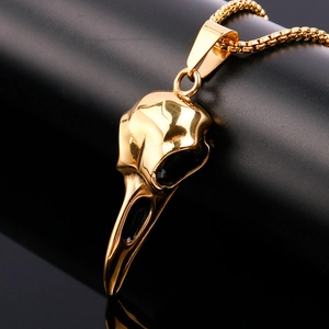 Detailed view of a golden eagle skull pendant necklace on a sleek black surface