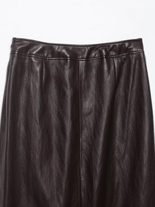 Détail de la jupe midi en cuir marron foncé avec ceinture et texture de couture