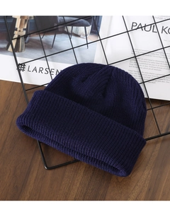 Detailed close-up of dark blue knit beanie showing fine vertical ribbing texture and cuff