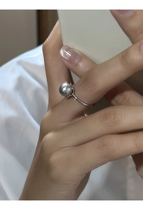 Primo piano di un anello argentato con una perla grigio argento tonda sulla mano di un modello