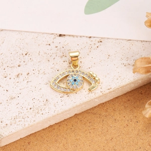 Detail shot of a gold-plated Evil Eye pendant with cubic zirconia on a stone surface