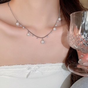 Elegant pearl tassel necklace with sparkling rhinestones worn by a model in soft lighting