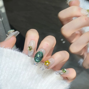 Sparkly handmade press-on nails featuring green gemstones, gold stars and silver sequins