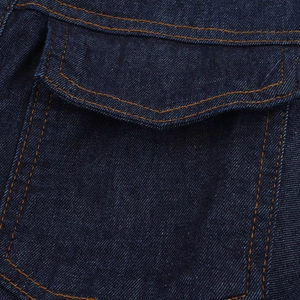 Detail van een donkerblauwe spijkerjurkzak met oranje contraststiksels en twill textuur