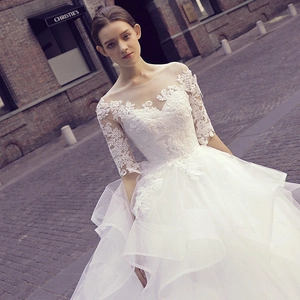 Elegant white lace wedding dress with illusion neckline and layered tulle skirt