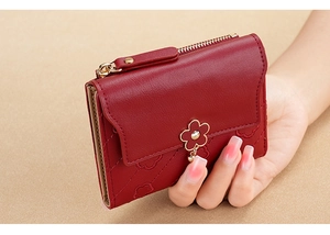 Red quilted PU leather short wallet with floral metal buckle held by a model