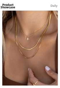 Detail of layered gold necklaces with snake chain box chain and S letter pendant