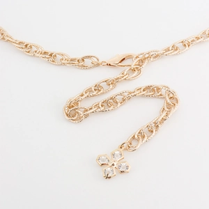 Close-up of gold chain belt featuring a lobster clasp and a sparkling clover charm