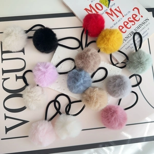 Detailed arrangement of colorful faux fur pom-pom hair ties on a stylish white stone surface