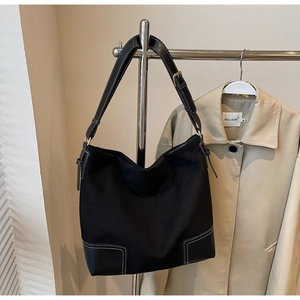 Detail of black tote bag with white contrast stitching and adjustable leather strap