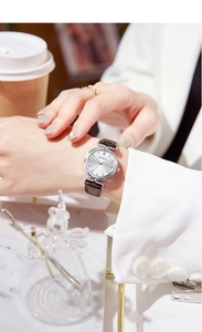 Elegant woman wearing a vintage silver dial watch with brown leather strap in a cafe setting
