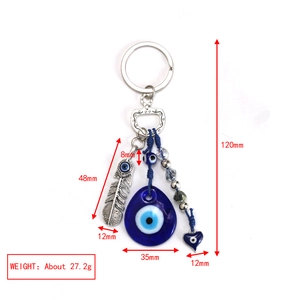 Detail of blue evil eye keychain with silver feather and heart charm pendants