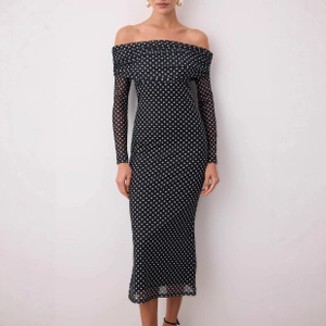 Close-up of off-shoulder mesh midi dress with white polka dots on black fabric