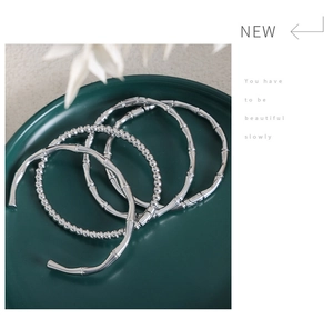 Silver-toned bamboo style open bangles and bead bracelet set in a green ceramic tray