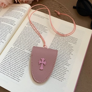Pink leather magnetic eyewear holder necklace with cross detail on an open book