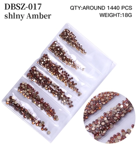Detail view of shiny amber crystal nail art rhinestones in a compartment storage tray