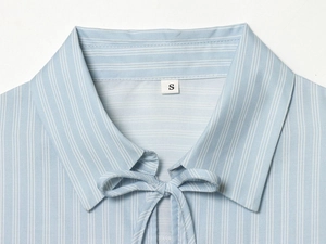 Détail d'une chemise à rayures bleu clair avec nœud papillon et étiquette de taille S