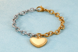 Detailed macro of two-tone gold and silver chain bracelet with beaded heart charm