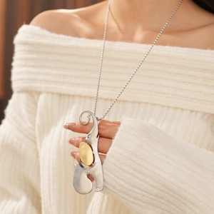 Détail du pendentif éléphant abstrait en argent mat avec accent doré sur un pull
