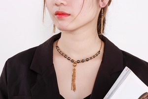 Dettaglio del set collana e orecchini con frange dorate e pietre naturali grigio scuro