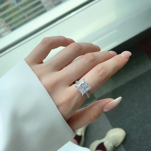 Close-up of a square princess cut sparkling diamond ring on a hand in natural light