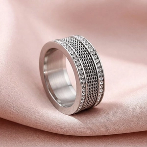 Macro detail of silver punk style ring with braided mesh center and double row of rhinestones