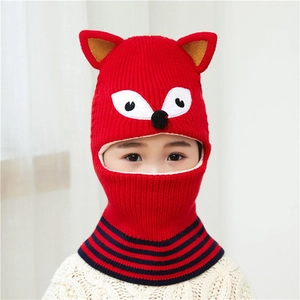 Close-up of red knitted children's balaclava with cute fox ears and striped collar detail