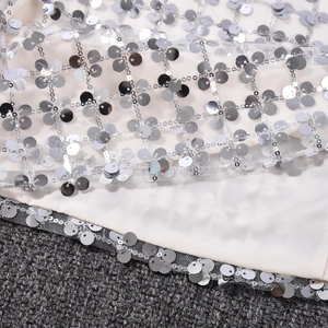 Gros plan de paillettes argentées sur tissu en maille blanche pour une robe à paillettes
