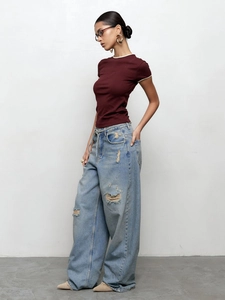 T-shirt bordeaux ajusté et jean large vieilli porté par un mannequin pour un look décontracté