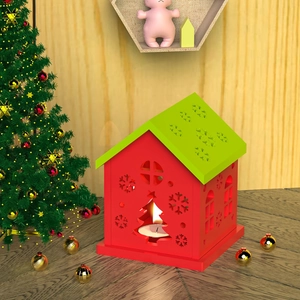 Detalle de un portavelas con forma de casa de Navidad en rojo y verde con calados