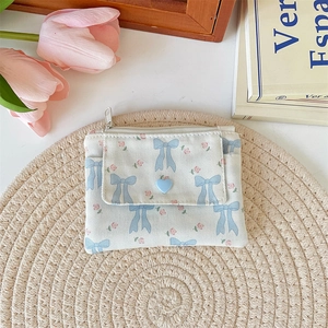 Close-up of fabric coin purse with blue bow, floral patterns and heart-shaped clasp