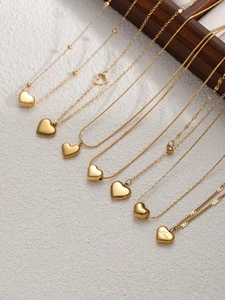 Dettaglio di otto collane a cuore dorate con incisione Love su supporto in legno