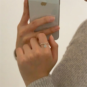 Close-up of minimalist 925 sterling silver beaded ring with round charm on finger