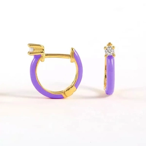 Close-up of golden earrings with purple enamel and sparkling crystal inlay