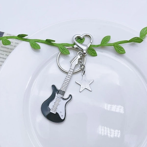 Detail of Y2K guitar keychain with black and white enamel finish and star charm pendant