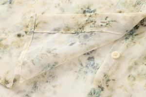 Vue macro du tissu popeline floral avec bouton blanc et couture détaillée sur le haut