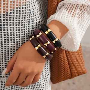 Three-piece bohemian acrylic beaded bracelets with gold accents on a female model