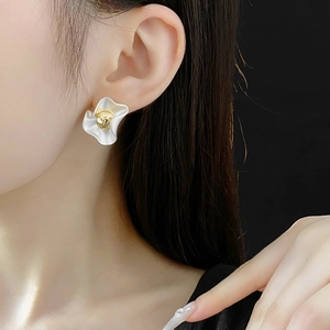 Detail of silver matte flower stud earring with gold center worn by a model