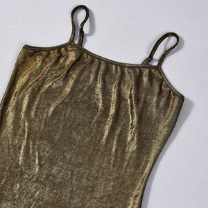 Close-up of golden backless dress fabric showing detailed metallic knit texture