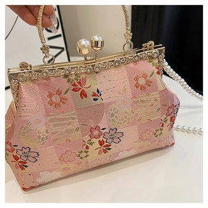 Close-up of pink satin evening bag with floral embroidery, pearls and tassel detail