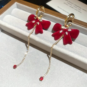 Detail of red flocked bow earrings with long sparkling tassels and red gemstones