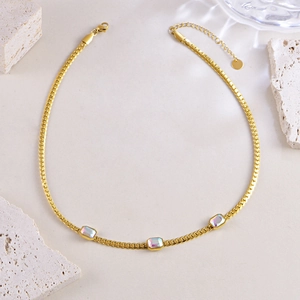 Elegant gold flat link necklace featuring three iridescent rectangular gemstones on a beige surface