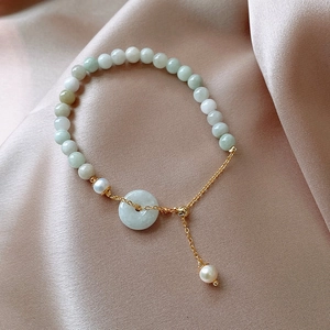 Detail of jade bead bracelet with pearl accents and adjustable gold chain on silk