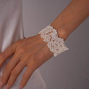 Détail du bracelet ouvert argenté avec motif de dentelle florale évidée en trèfle
