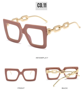 Detail of square oversized glasses in dusty pink featuring golden chain design temples