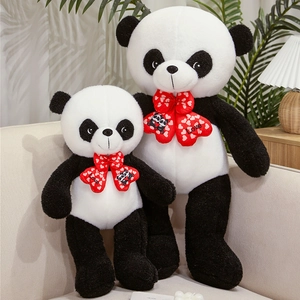 Close-up of fluffy panda plush set with red 'Love' heart bows on a cozy beige sofa