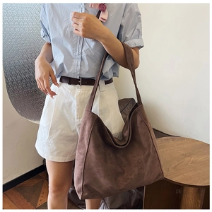 Close-up of brown suede tote bag showing premium texture on a model wearing casual outfit