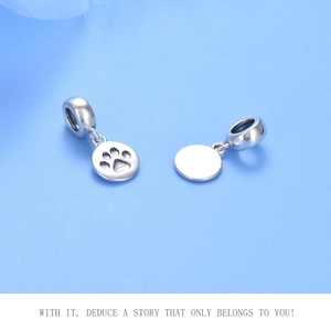 Macro shot of 925 sterling silver pet paw charms with S925 hallmark on blue background