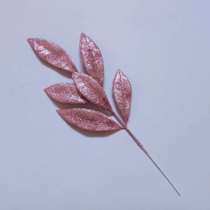 Dettaglio di foglie di pino artificiali in oro rosa glitterato per decoro natalizio