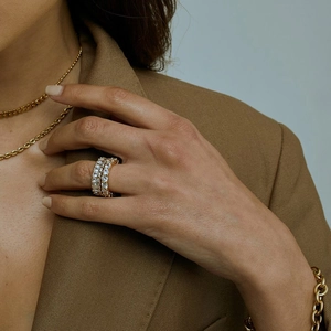Detail of stacked gold zircon rings worn by a model in professional brown blazer
